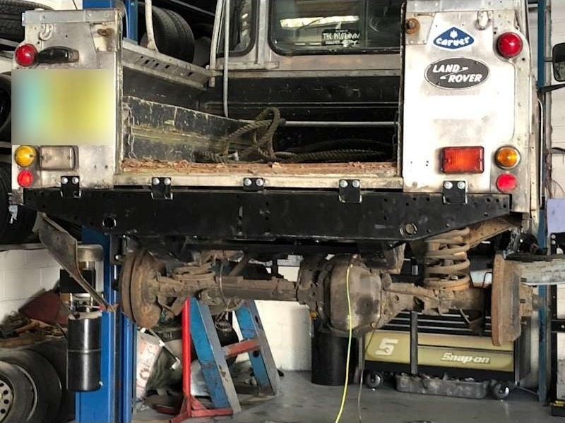 Vehicle raised on the workshop lift, rear axle and suspension in view